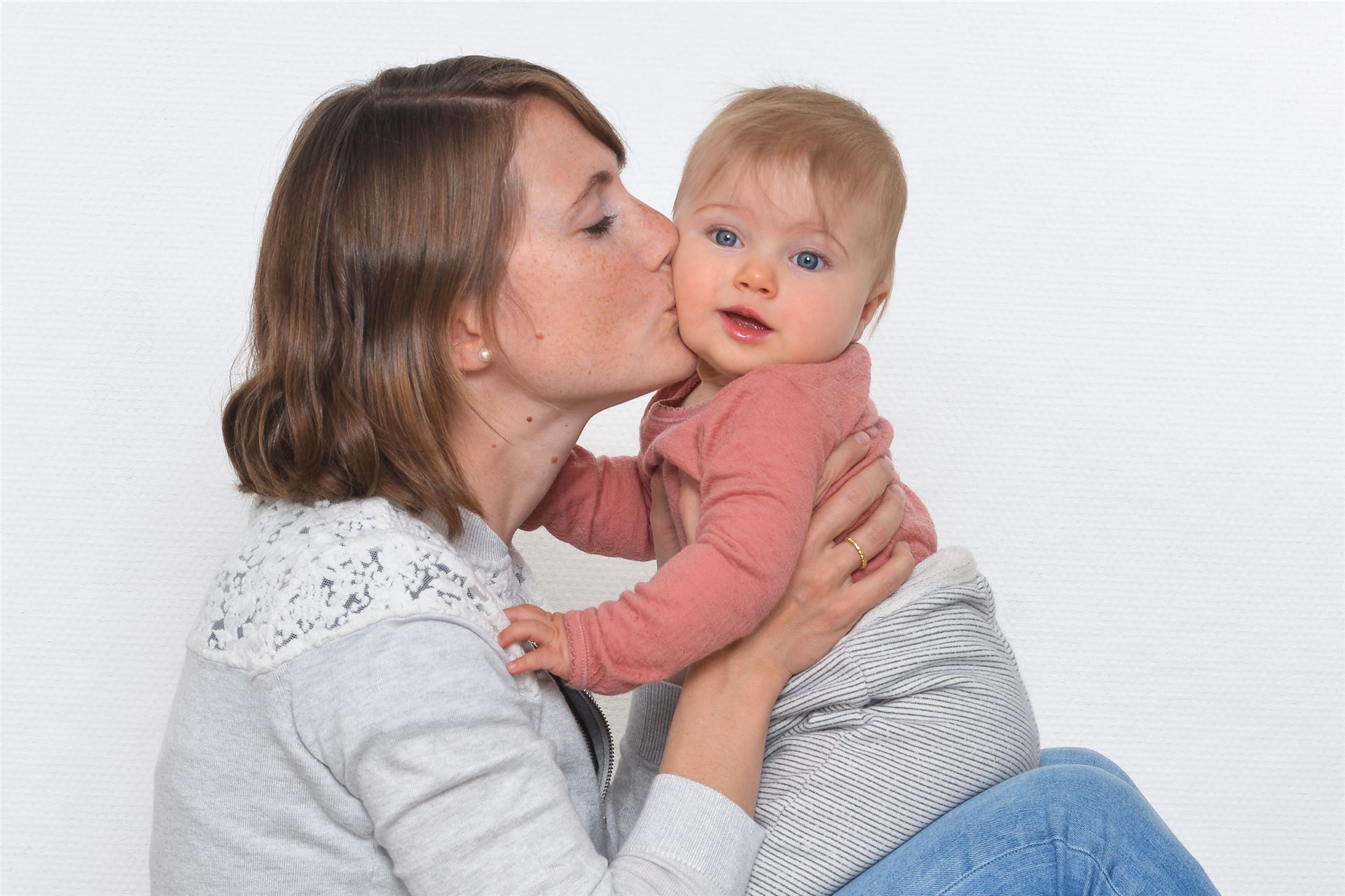 Mutter k&uuml;sst ihr Baby bei einem emotionalen Familienshooting